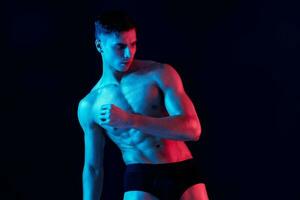 sexy guy with athletic physique posing on a black background photo