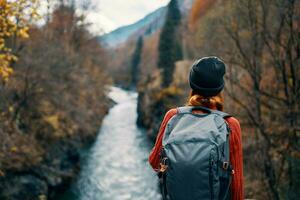 woman hiker backpack river travel to the mountains photo
