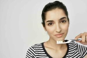 brunette in a striped t-shirt toothbrush in hand light background photo