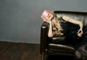 A woman with a pink sleep mask lies on the couch with a bottle of beer in her hand photo