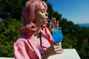 Delighted young girl enjoying a colorful cocktail hotel terrace Happy female relaxing photo