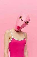 Funny crazy woman on a pink background standing in a fish head mask on a pink background, conceptual Halloween costume art photo