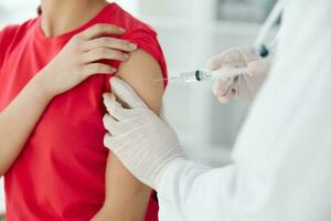 a doctor injects a vaccine into the shoulder of a woman patient close-up photo