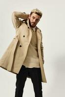 young man in beige coat dark pants sweater model photo