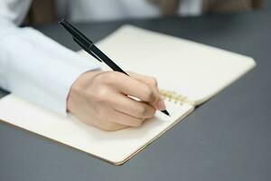 Closeup shot of hand young student lady freelancer journalist writing article using copybook in gray modern home office. Remote Job, Education And Career Profession Concept. Copy space photo