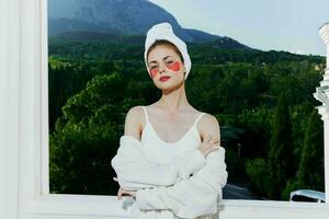 Woman in a bathrobe stands in a robe against the backdrop of mountains with patches on his face close-up photo