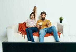 man and woman on the couch watching tv flower potted photo