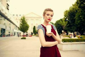 short haired woman outdoors fashion posing glass with drink photo