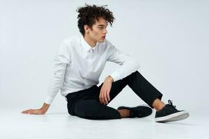 teenager in sneakers, black trousers and a white shirt In a bright room in full growth photo