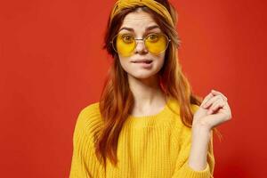 woman in yellow glasses with a bandage on her head yellow sweater Hipster red background photo