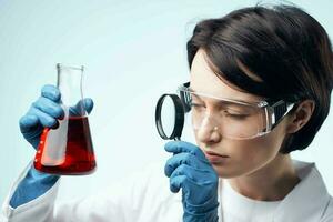 female laboratory assistant looks through a magnifying glass at a biochemical research process photo