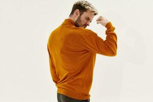 strong man shows his arm muscles and orange sweater blond Copy Space photo