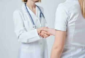 Doctor and patient shake hands with each other on a light background cropped view photo