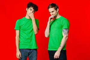 Cheerful friends in green t-shirts gesturing with hands emotions photo