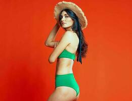 woman in green swimsuit beach hat summer vacation red background photo