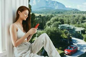 alegre mujer con un rojo teléfono terraza al aire libre lujo paisaje ocio inalterado foto