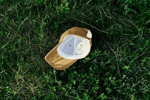 A yellow sports cap lies upside down on the green grass. Spring outdoor sports games photo