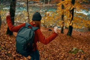 woman with backpack travel tourism forest landscape park river fallen leaves side view photo