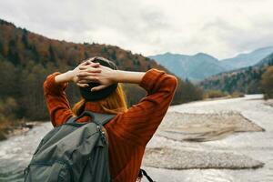 woman traveler on vacation in the mountains in nature near the river hold hands behind her head photo