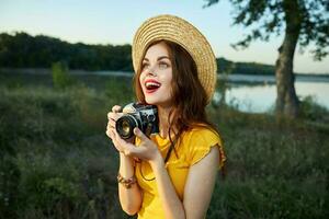 Woman with a camera looks up in a hat red lips open mouth nature photo