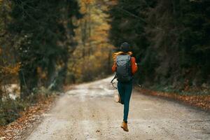 happy traveler with backpack walks on the road in autumn forest photo