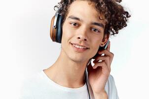 guy with curly hair in headphones listens to music on a light background photo