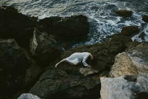 sensual woman in a white dress lying on a stone in a white dress Summer vacation concept photo