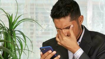 young stressed businessman sits alone looking at phone video