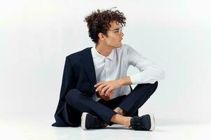 emotional guy in a classic suit sits on the floor in a bright room glasses on the face portrait model photo