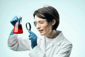 female laboratory assistant looking through a magnifying glass at a chemical solution analysis diagnostics photo