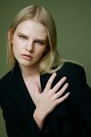 A close portrait of a blonde crossing her arms on her chest holding a jacket by the collar photo