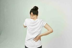 woman in white t-shirt holding her lower back health problems photo