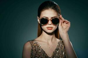 woman wearing sunglasses golden dress studio luxury dark background decoration photo