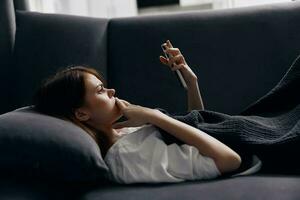 woman on sofa looking at mobile phone screen and soft pillow photo