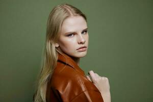 Unbelievable beautiful stylish woman posing in leather dress at over green studio background photo