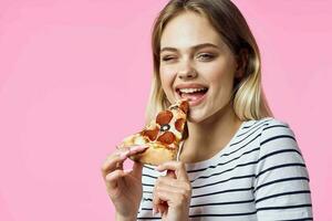 mujer en a rayas camiseta con Pizza en manos rápido comida bocadillo rosado antecedentes foto