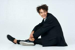 chico con Rizado pelo en un traje sentado en el piso Moda auto confianza foto