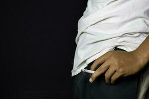 Hand of asian man holding cigarettes with black background. Smoking cigarettes concept photo