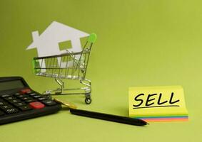 House put in a shopping cart and coin, calculator on the desk. Savings for home, buying houses, sell houses, real estate or housing benefit concept. photo