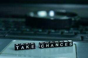 Take Chances text wooden blocks in laptop background. Business and technology concept photo