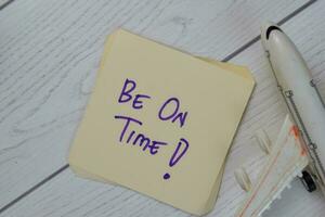 Be On Time write on sticky notes isolated on Wooden Table. photo