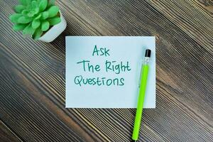 Concept of Ask The Right Questions write on sticky notes isolated on Wooden Table. photo