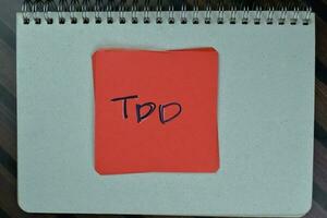 TDD write on sticky notes isolated on Wooden Table. photo