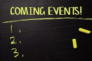 Coming Events written with color chalk. Supported by an additional services. Blackboard concept photo