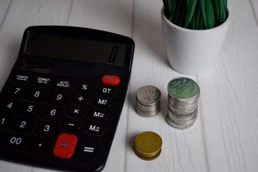 Calculator and the stack of coint isolated on office desk. calculating salary or tax concept photo