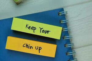 Keep Your Chin up write on sticky note isolated on Wooden Table. photo