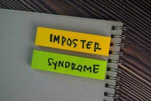 Imposter Syndrome write on sticky notes isolated on Wooden Table. photo