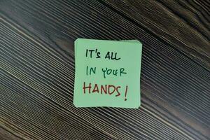 Concept of It's All In Your Hands write on sticky notes isolated on Wooden Table. photo