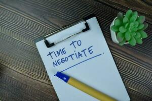 Time To Negotiate write on a paperwork isolated on Wooden Table. photo
