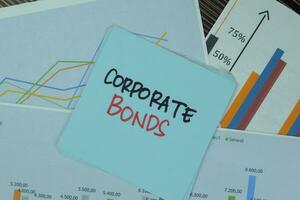 Corporate Bonds write on sticky notes isolated on Wooden Table. photo